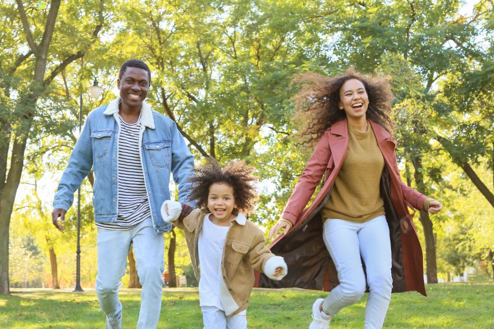 A family laughing and running together through a park