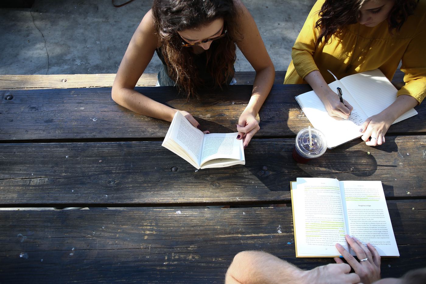 A small group reading and writing together at a picnic table